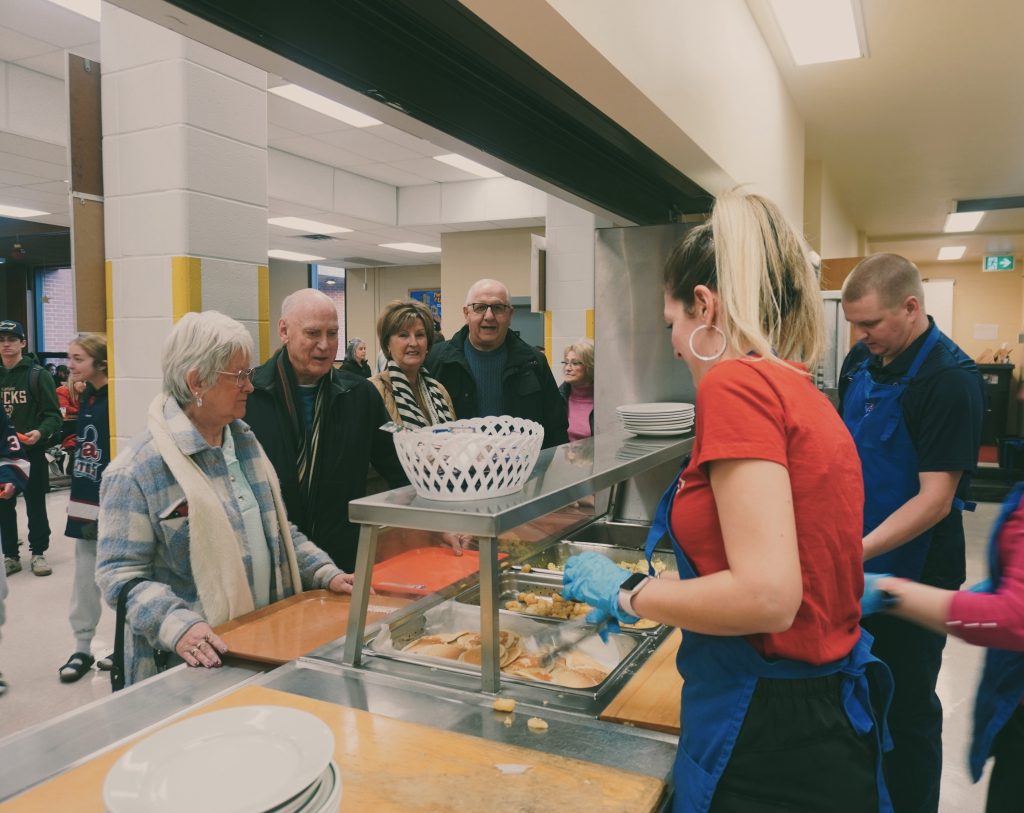 Des membres de la communauté recevant leur repas, lors du Déjeuner communautaire de Noël de la polyvalente Thomas-Albert.